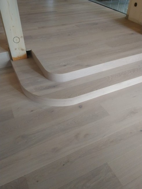 Holzstufen mit abgerundeten Kanten auf einem hellen Holzboden