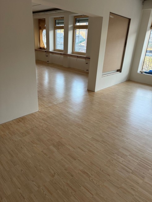 Heller Raum mit gro&szlig;en Fenstern und Holzboden