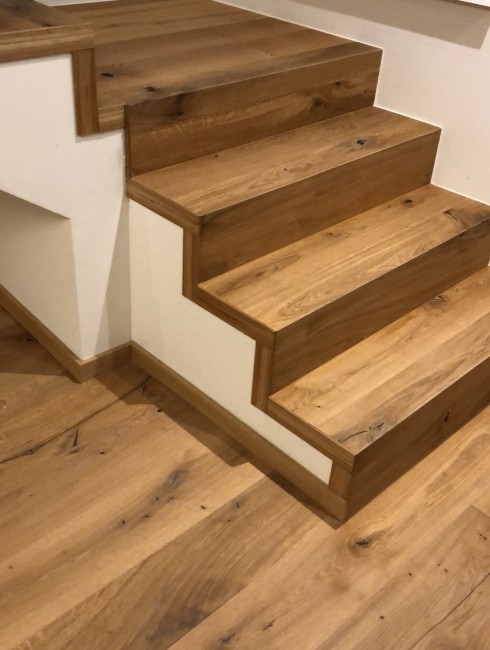 Holztreppe mit hellbrauner Maserung und wei&szlig;en W&auml;nden